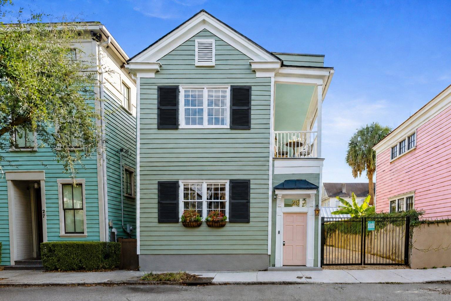 Breezy Palm, a sage green Charleston single house with a pink door